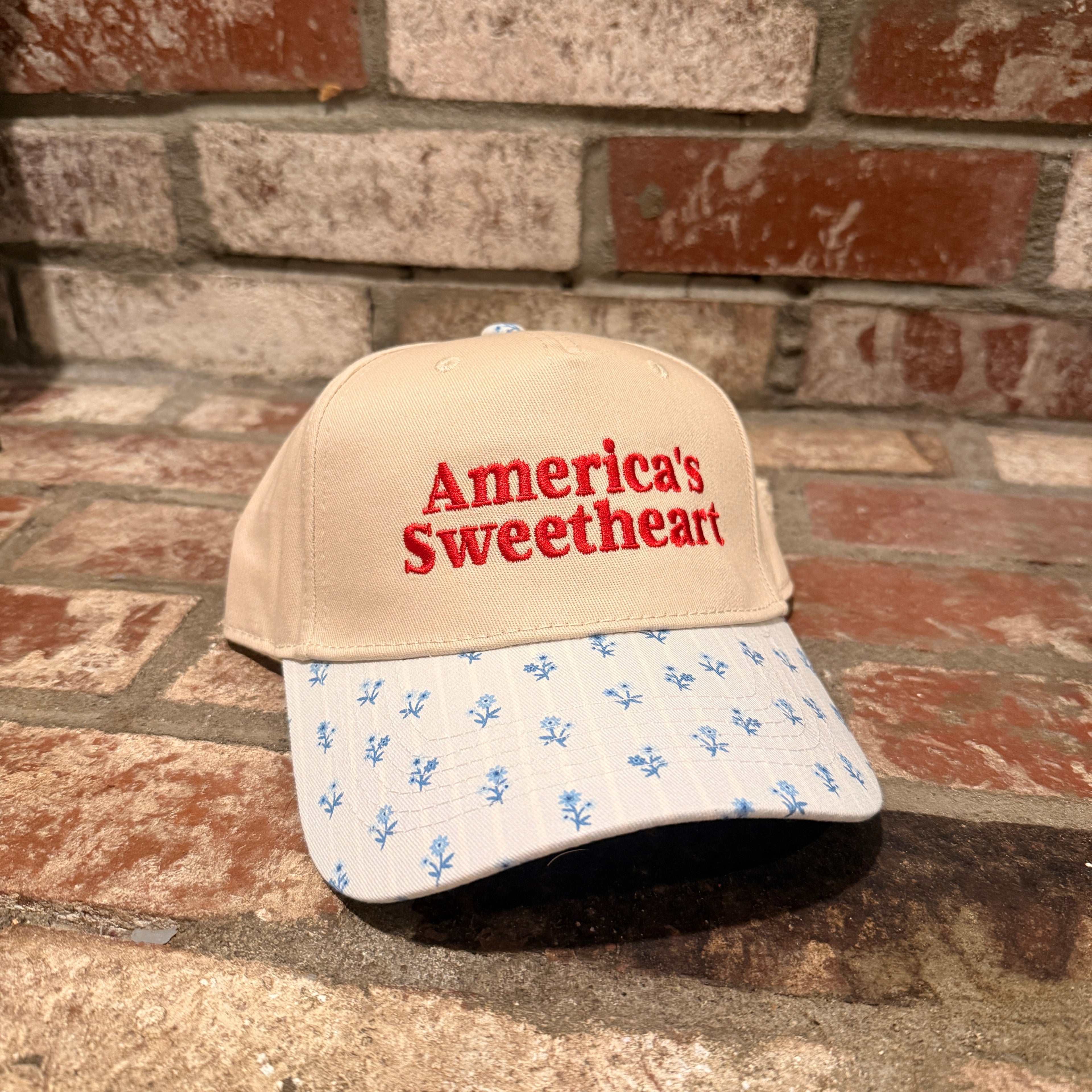 Cap with 'America's Sweetheart' text on a brick surface