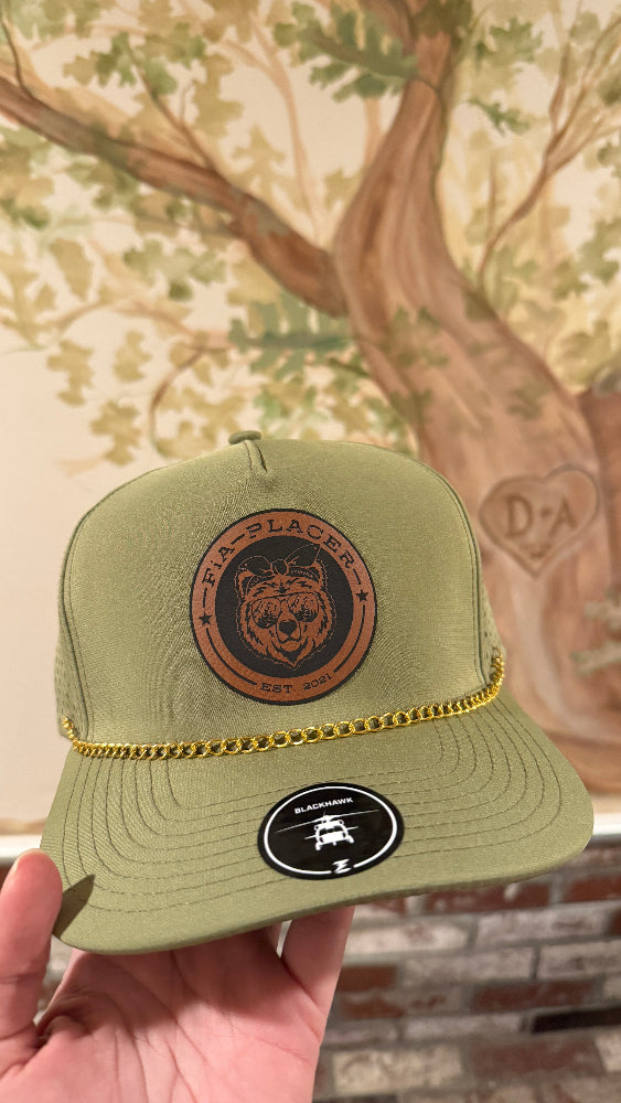 Green trucker hat with leather patch held in front of a decorative wall.