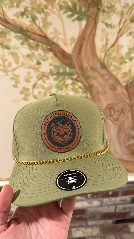 Green trucker hat with leather patch held in front of a decorative wall.