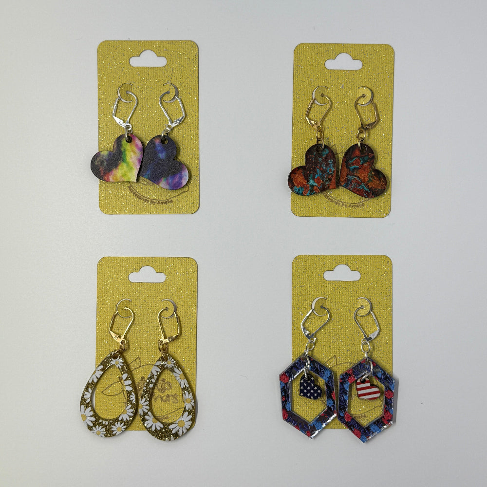 Four pairs of handcrafted Wood or acrylic earrings on yellow cards against a white background