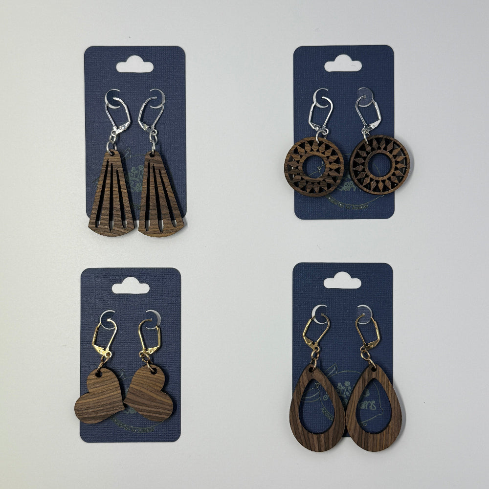 Four pairs of handcrafted wooden earrings on blue cards against a white background