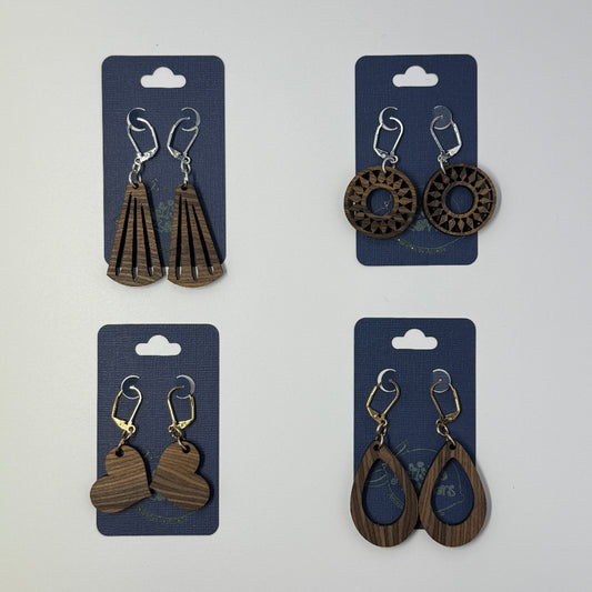 Four pairs of handcrafted wooden earrings on blue cards against a white background